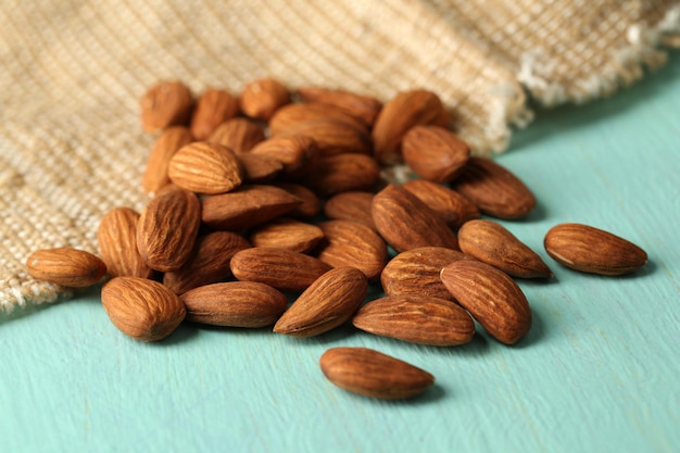 Almonds on color wooden table on sackcloth background