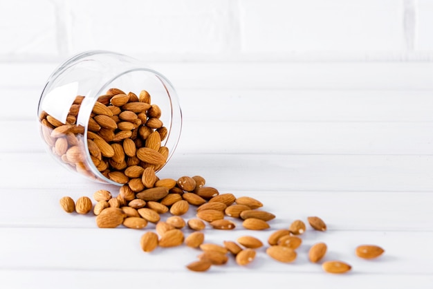 Almonds in glass bowl on white background.