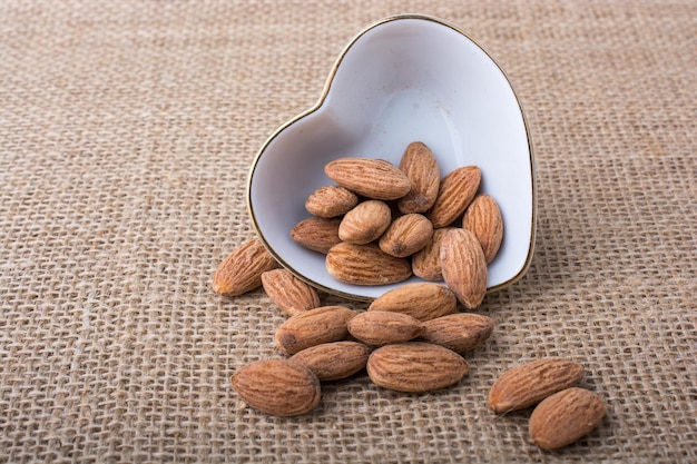 Almonds in a heart shaped plate on canvas