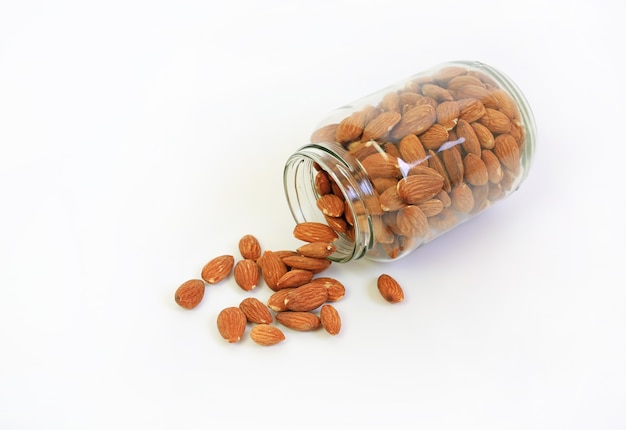 Almonds nuts pour from glass bottle isolated on a white background