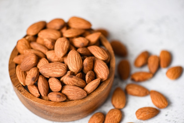 Almonds nuts on wooden bowl on table background