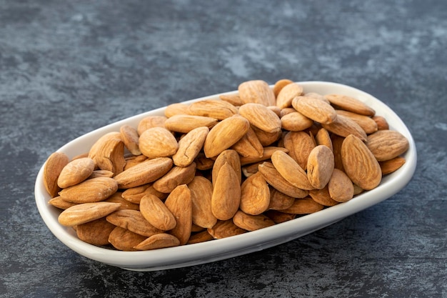 Almonds on plate on dark background