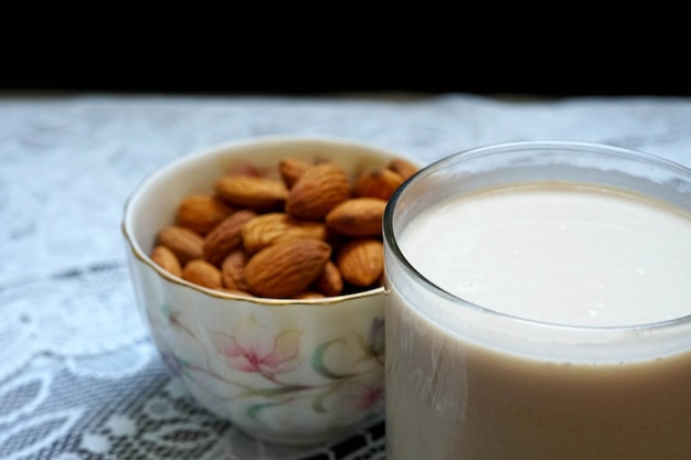 Almonds in a small bowl with a glass of almonds milk