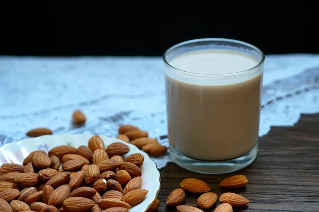 Almonds on a white plate with a glass of almonds milk