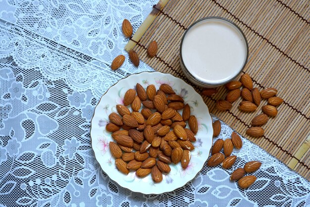 Almonds in a white plate with a glass of almonds milk