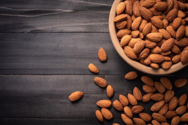 Almonds in wooden bowl on dark wood table Almond concept with copyspacetopview