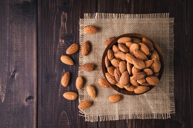 Almonds in a wooden bowl on dark wooden table