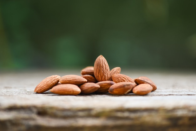 Almonds on wooden table and blurred nature / Close up almond nuts natural protein food and for snack