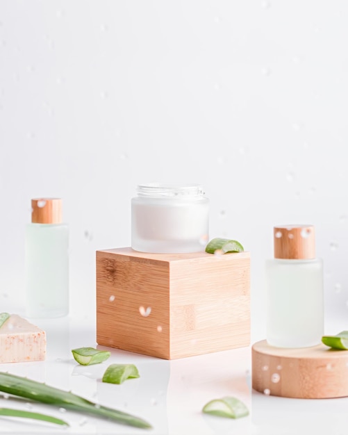 Aloe vera face serum and cream in reusabe bottles on wooden stands on white background Concept of natural cosmetics with aloe vera plastic free clean natural look