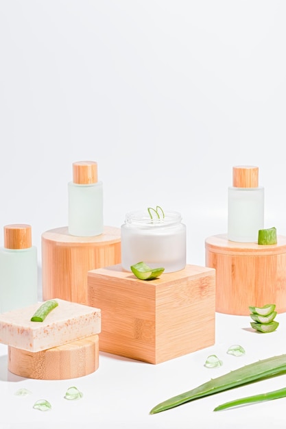 Aloe vera face serum and cream in reusabe bottles on wooden stands on white background Concept of natural cosmetics with aloe vera plastic free clean natural look