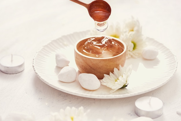 Aloe vera gel on a bowl, with chrysanthemum and candle in stone table