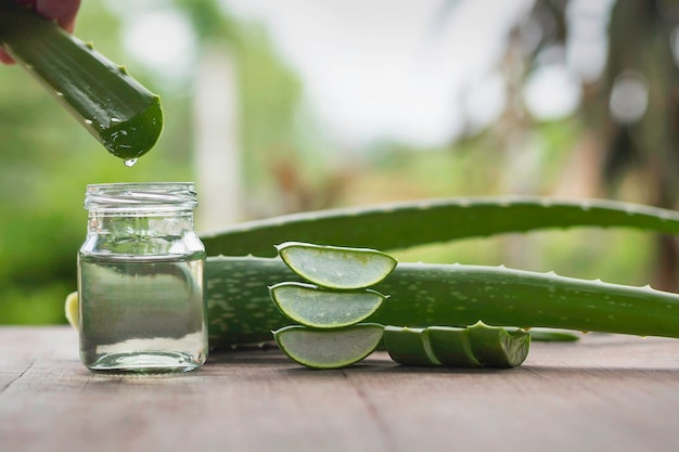 Aloe vera leaves and a glass of water laid on the wooden floor