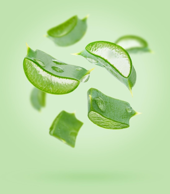 Aloe vera slices flying composition on green background