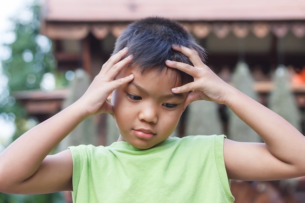 Alone Asian little boy feel sad, headache and stressed.