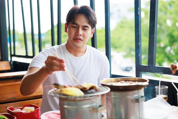 Alone asian man grill food on grille charcoal stove at grilled restaurant