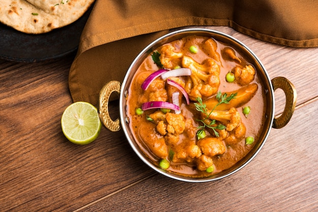 Aloo Gobi mutter is a famous Indian curry dish with potatoes and cauliflower and green peas, selective focus