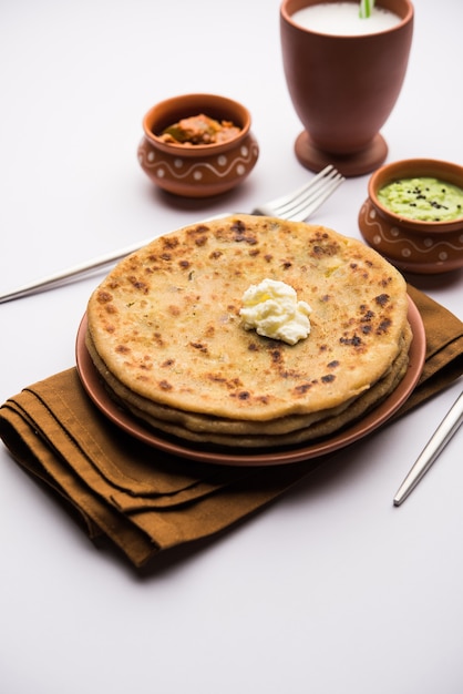 Aloo Paratha or Indian Potato stuffed Flatbread with butter on top. Served with fresh sweet Lassi, chutney and pickle . selective focus