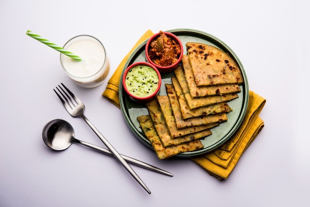 Aloo Paratha or Indian Potato stuffed Flatbread with butter on top. Served with fresh sweet Lassi, chutney and pickle . selective focus