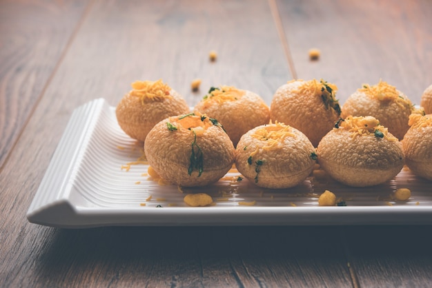 Aloo Sev Puri is a popular Indian roadside chat item, served in a white plate. Top view, selective focus