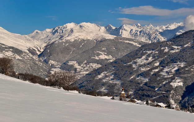 Alpine village in tarentaise valley view on snowcapped mountains under blue sky