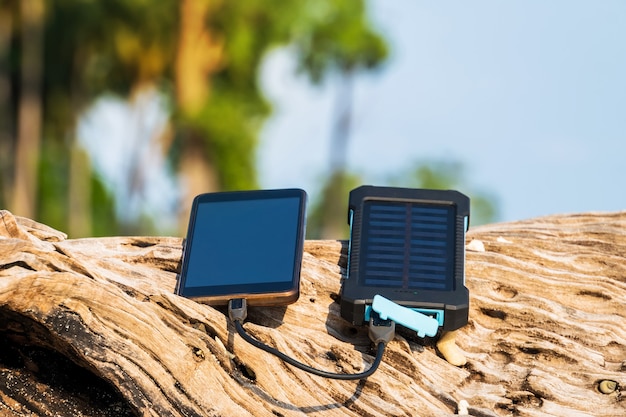 Alternative energy source. battery is charged by solar energy. Charging mobile devices in the wild. island beach. Powerbank charges the phone on the background of palm trees and sandy beach