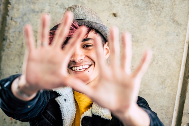 Alternative happy and cheerful diverse teenager hide his face and smile with hands