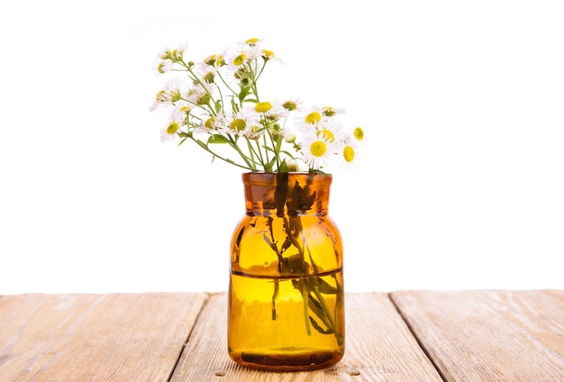 Alternative medicine concept bottle with camomile on wooden table