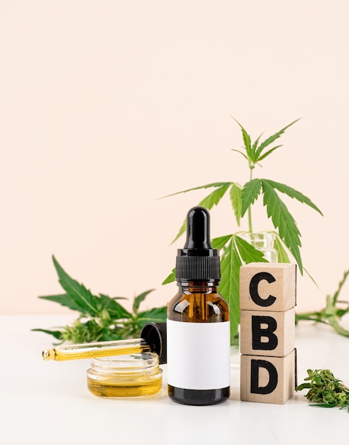 Alternative medicine, natural cosmetics. cbd oil and cannabis leaves cosmetics front view on orange background, copy space