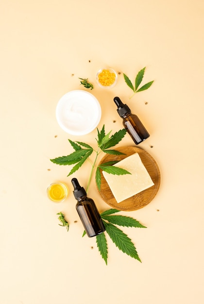 Alternative medicine, natural cosmetics. cbd oil and cannabis leaves cosmetics top view on orange background, flat lay