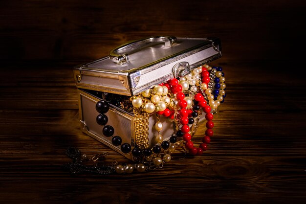 Aluminium case full of different jewelry on rustic wooden table