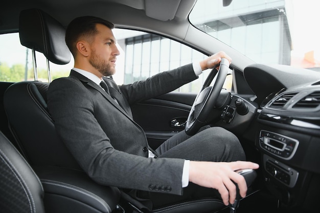 Always in a hurry Handsome young man in full suit smiling while driving a car