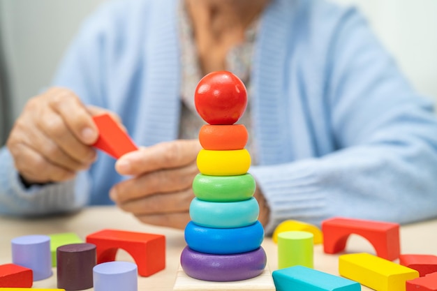 Photo alzheimer disease ad asian elderly woman patient suffering from dementia learn practical motor skills rehabilitation