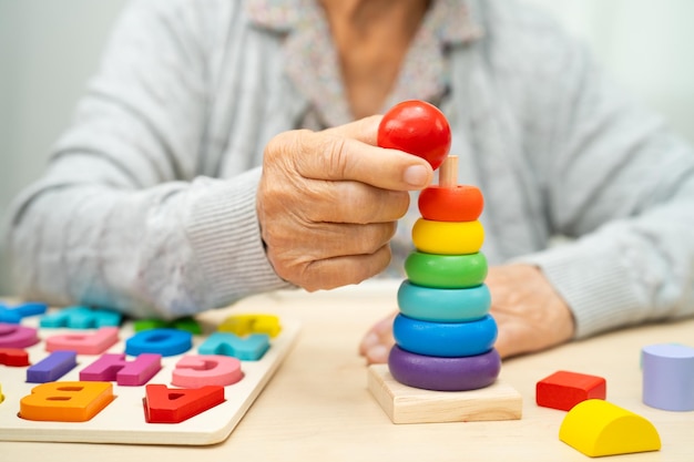 Photo alzheimer disease ad asian senior woman patient suffering from dementia learn practical motor skills rehabilitation