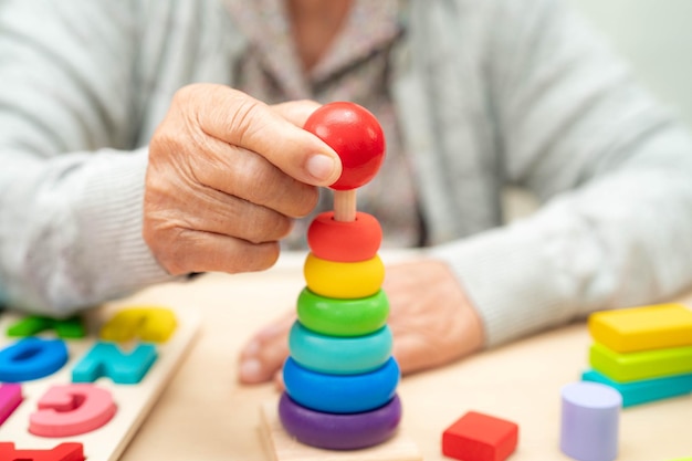 Photo alzheimer disease ad asian senior woman patient suffering from dementia learn practical motor skills rehabilitation