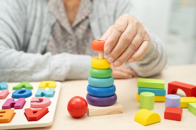 Photo alzheimer disease ad asian senior woman patient suffering from dementia learn practical motor skills rehabilitation