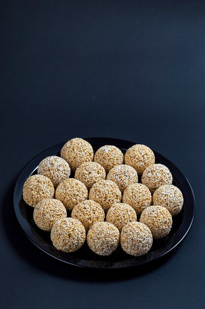 Photo amaranth ladoo or rajgira laddu or cholai ke laddo in black plate on black background.