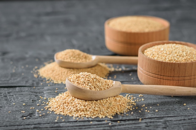 Amaranth and quinoa seeds and two wooden spoons on a table.