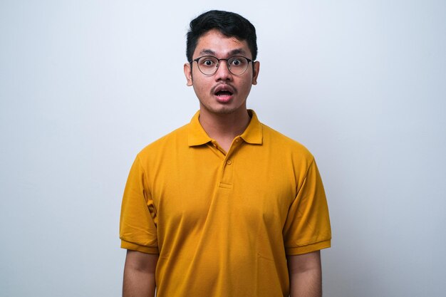 Amazed asian young man with open mouth and bulging eyes looking at camera isolated white background