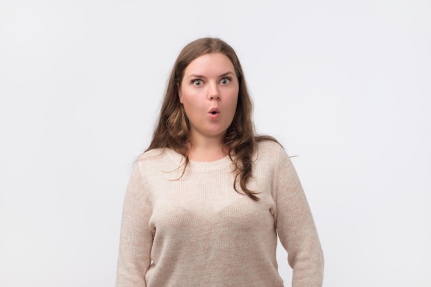 Amazed beautiful plump woman with long hair and attractive appearance looking with large eyes