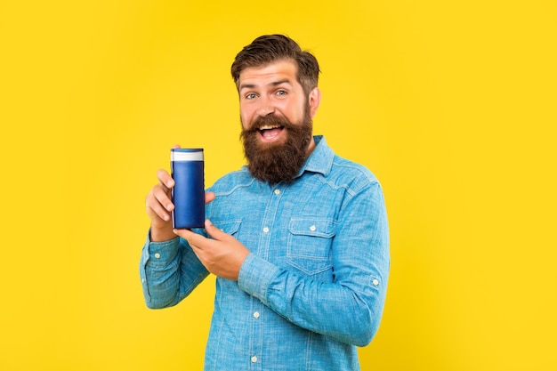 Amazed brutal bearded man hold hair conditioner bottle on yellow background haircare