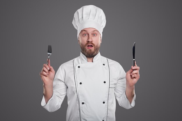 Amazed chef with knife and fork