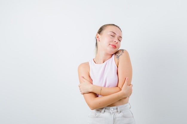 Amazed girl is hugging herself on white background