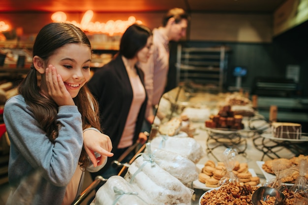 Amazed girl standing at shelf with candy and looking at them