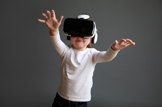 Amazed girl wearing virtual reality goggles watching movies or playing video games. Child experiencing 3D gadget.