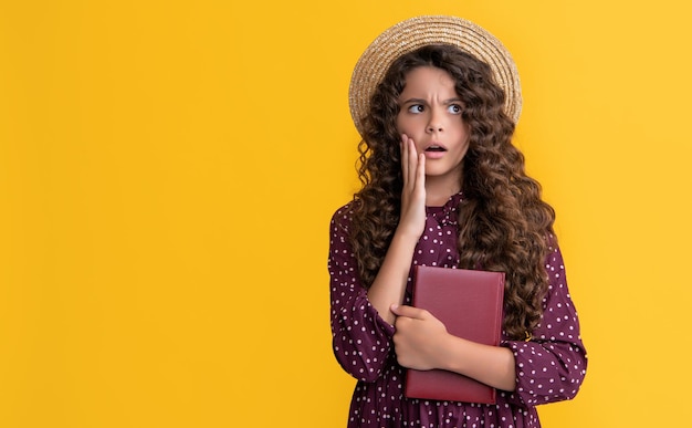 Amazed kid with frizz hair hold book on yellow background