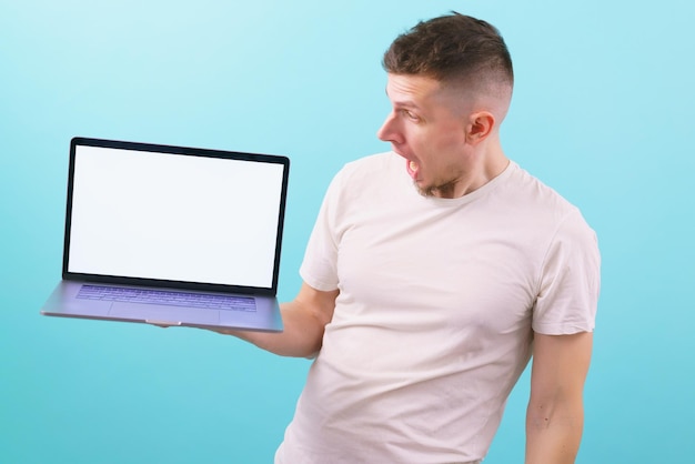 An amazed man holding a laptop with an empty blank screen and looking at it with an open mouth