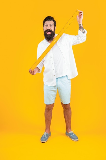 Amazed man with measuring ruler in studio man with measuring ruler on background