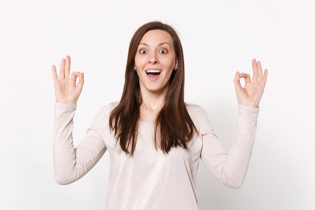 Amazed surprised young woman in light clothes hold hands in yoga gesture relaxing meditating isolated on white wall background in studio. People sincere emotions lifestyle concept. Mock up copy space.