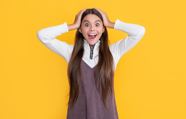 Amazed teen child with long hair on yellow background