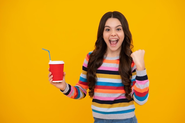 Amazed teenager Teenage girl with take away cup of cappuccino coffee or tea Child with takeaway cup on yellow background morning drink beverage Excited teen girl